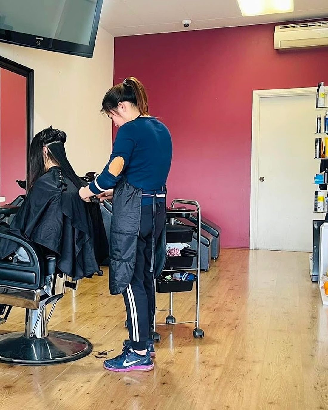 Stylist working on a client's long hair inside Babylon Hairdressing