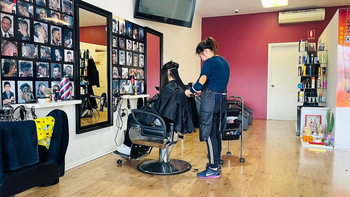Inside Babylon Hairdressing, a stylist cutting a client's hair